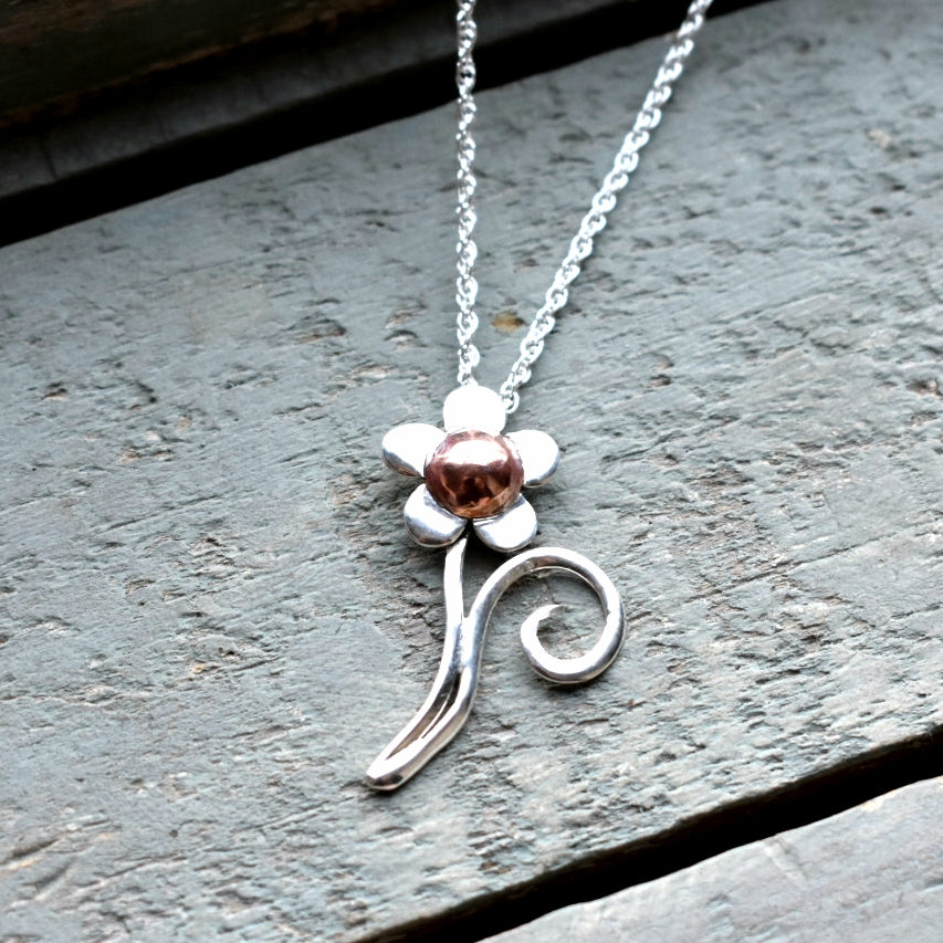 Silver flower pendant with a copper center. Pendant around 5cm in length.

Price doesn't include a chain. Chains can be ordered separately from our chain collection.

Please note all pieces are made on order by Erfdeel Juwele. Allow up to a week for manufacture. 


