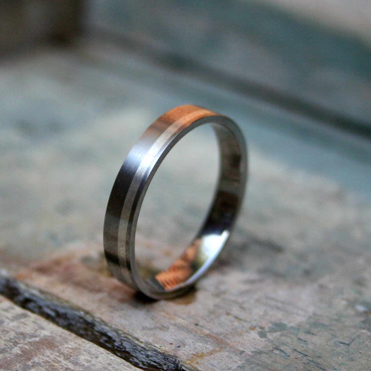 4mm Titanium flat top band with a 1.5mm silver inlay to one side. The ring is made with a matt finish and a comfort fit on the inside.  As a 4mm band this ring design can work well for both the ladies and the gents.