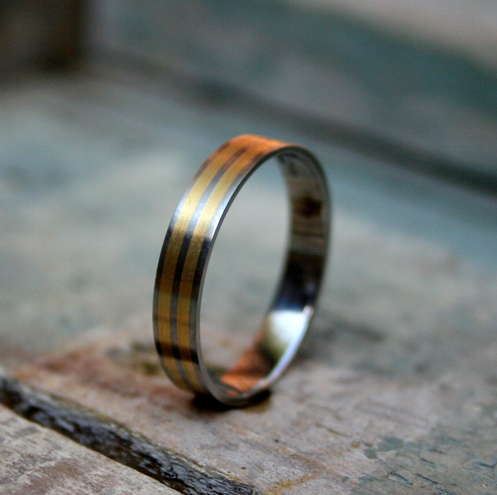 4mm Titanium flat top band with 2 1mm 9ct yellow gold inlays. The ring is made with a matt finish and a comfort fit on the inside.  As a 4mm band this ring design can work well for both the ladies and the gents.