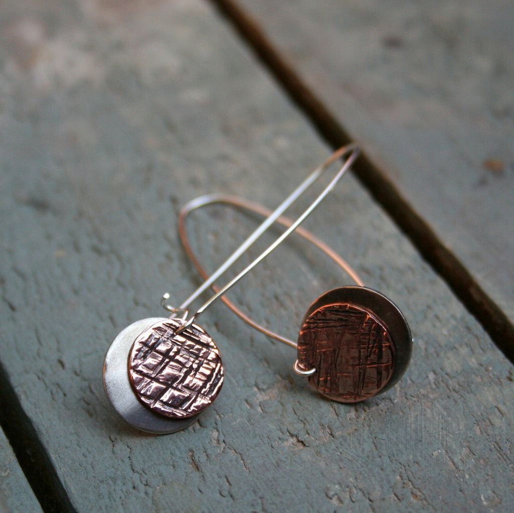 A polished 14mm copper disc with a hammered textured finish over a matt 16mm silver disc on long sterling silver hooks.   Please note all pieces are handmade on order by Erfdeel Juwele. Allow up to two weeks for manufacture.