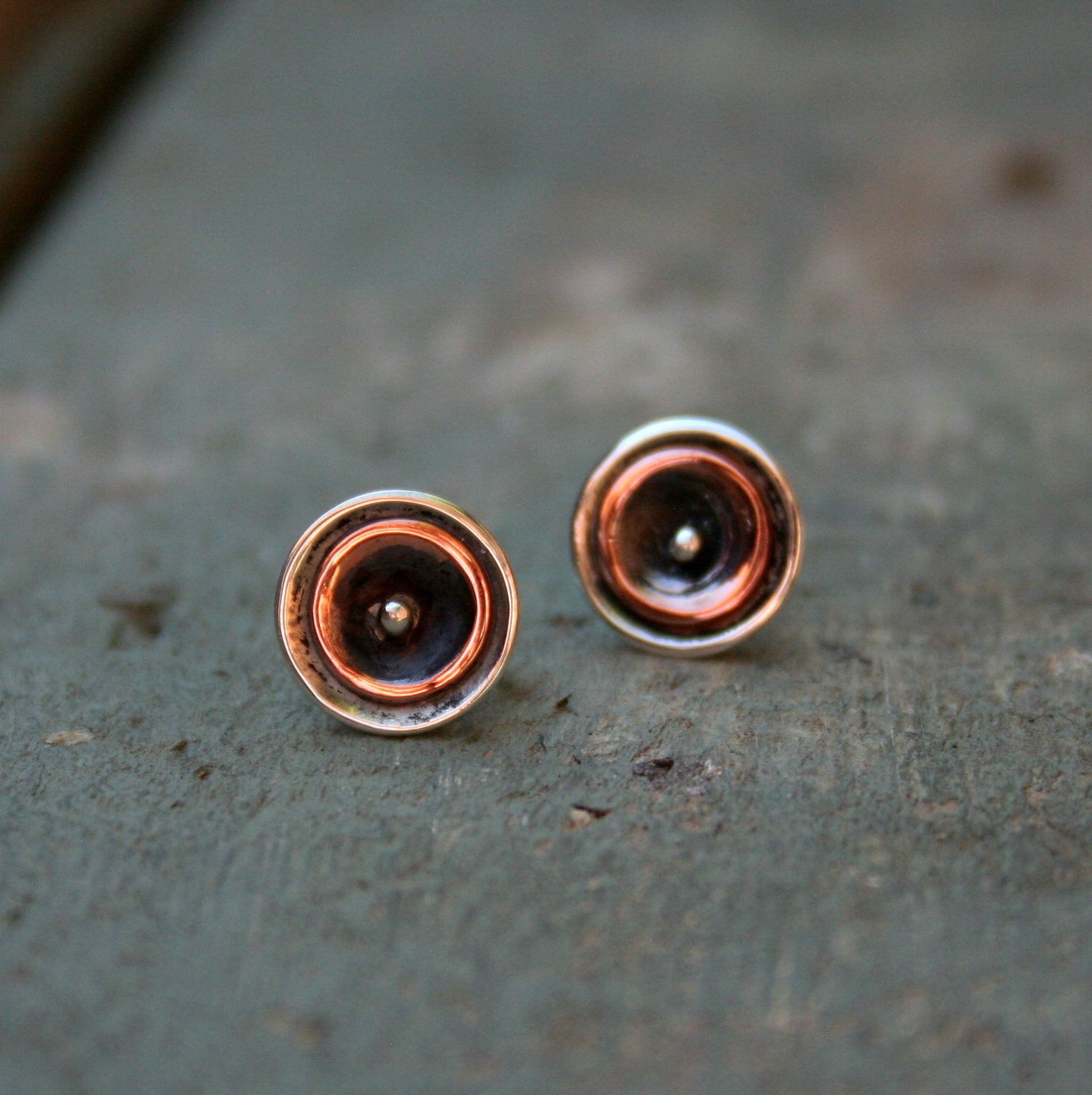 A domed sterling silver disc stud with a smaller copper disc and silver dot inside.  Please note all pieces are handmade on order by Erfdeel Juwele. Allow up to two weeks for manufacture.